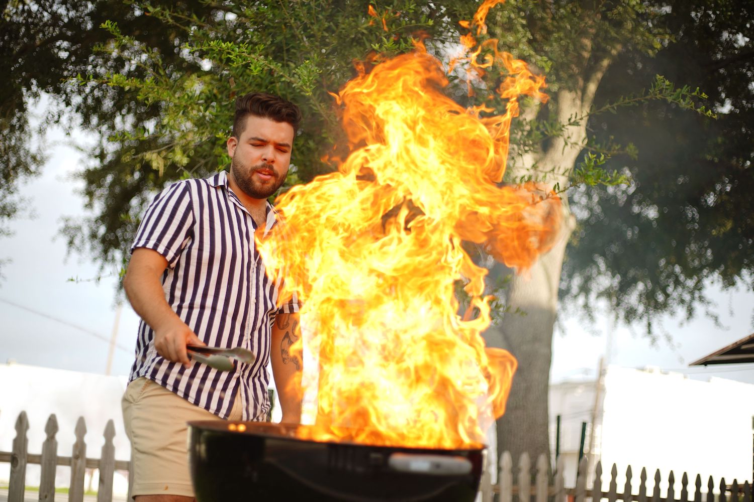 man grilling turkey over flame grill